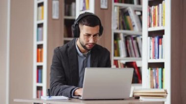 Dizüstü bilgisayarda çalışırken müziğe yönelen adam