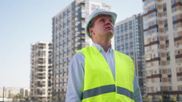 Інженер, який дивиться на будівлі в новому міському районі — стокове відео