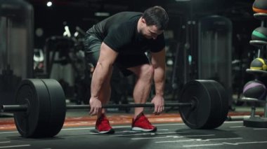 Spor salonunda halterle çalışan kaslı bir adam.