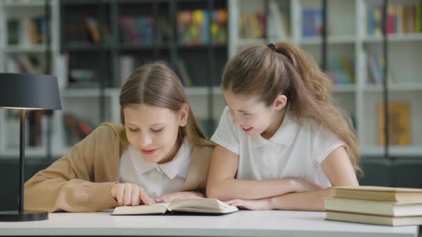 Dos Chicas Escuela Sentadas Juntas Mesa Una Leyendo Libro Divertido — Vídeos de Stock