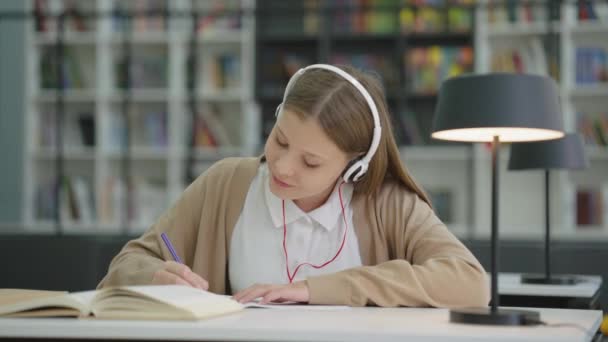 Ragazza Della Scuola Indossando Cuffie Scrivere Compiti Ascoltare Musica Godendo — Video Stock