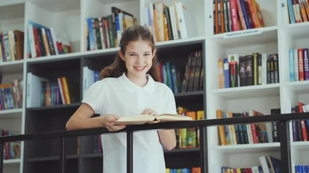 Gelukkig Meisje Met Een Wit Shirt Bij Boekenplanken Een Boek — Stockvideo