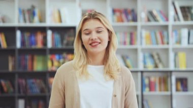 Kadın blog yazarı etkileyicisi kamerayla konuşuyor, video kaydediyor ya da konferans görüşmesi yapıyor, arka plandaki kitaplıklar bulanık. İnternette röportaj veren bir kız. Kütüphanede sunum yapan öğrenci