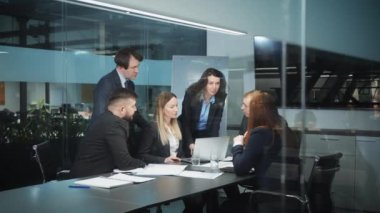 Resmi giyinen iş adamları modern ofiste toplanıyor, başarılı yöneticiler projeyi tartışıyor, fikirleri paylaşıyor, cam duvarın arkasından çekim takip ediyorlar. Takım çalışması kavramı