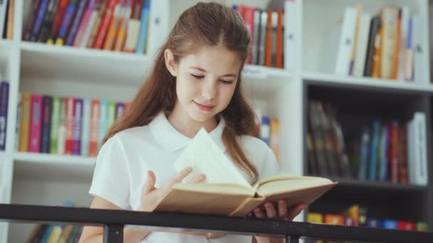 Glimlachend Kind Met Wit Poloshirt Bij Metalen Leuningen Leesboek Boekenplanken — Stockvideo