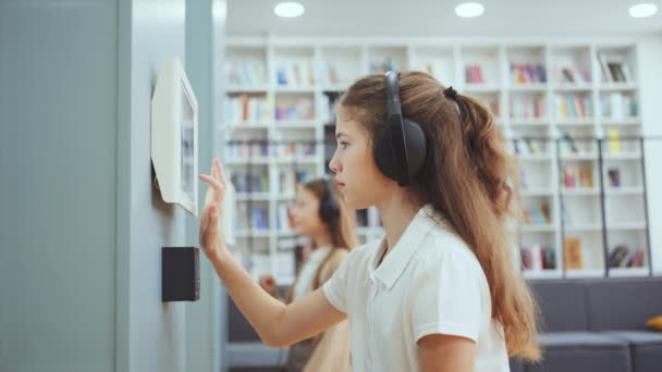 Öğrenci Kulaklık Takıyor Duvara Bağlı Bir Cihaz Kullanıyor Ekranına Dokunuyor — Stok video