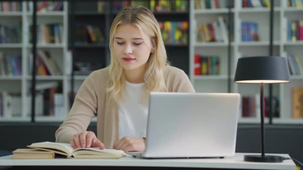 Blonde Teenage Girl Sitting Table Laptop Reading Book Looking Side — Stockvideo