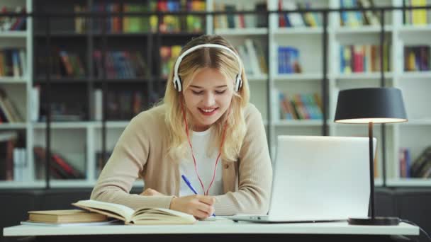 Happy Teenager Wearing Headphones Sitting Desk Writing Notebook Laptop Front — Stock videók