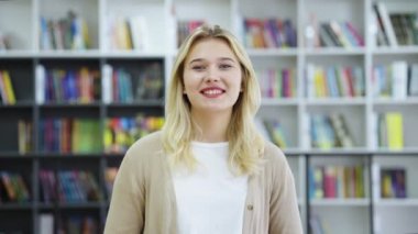 Genç, neşeli kadın blogcu etkileyicisi kamerayla konuşuyor, görüntülü konuşma veya konferans görüşmesi yapıyor. Röportaj veren mutlu kız. Kütüphanede üniversitesiyle ilgili vlog kaydeden öğrenci