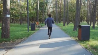 Kıvırcık saçlı, sonbahar parkında koşan, yere düşen yapraklı, ağır çekim zinde bir adam. Sabah koşucunun egzersiz çekimini takip ediyorum. Sağlıklı yaşam tarzı kavramı