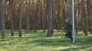Sonbahar spor kıyafetlerinde yavaş çekim formundaki adam parkta koşuyor, ağaçların arasında güneş parlıyor. Atış talimi dışarıda yapılıyor. Zindelik kavramı