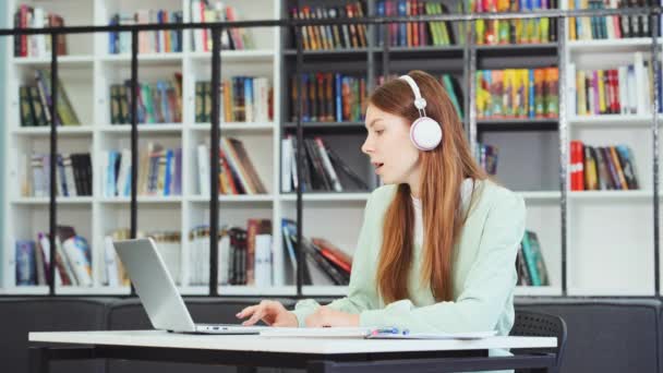 Biała Studentka Słuchawkach Studiująca Bibliotece Słuchająca Muzyki Pracująca Laptopem Śpiewająca — Wideo stockowe