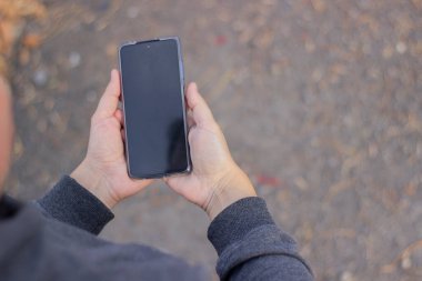 Yakından bakınca, erkek eli boş ekranlı akıllı telefon tutuyor. Model mesaj ya da içerik için hazır. Cep telefonlu bir adamın elleri. Boş ekran.