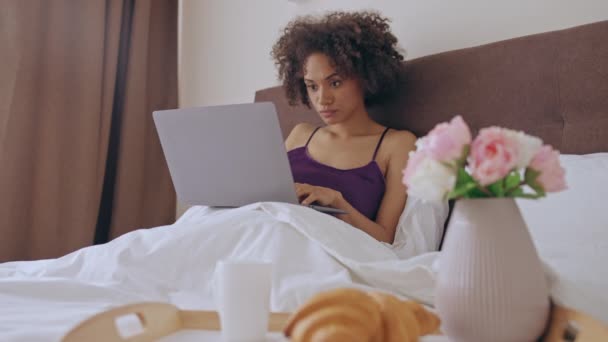 非洲裔美国妇女在床上用笔记本电脑工作 面带微笑 喜欢自由职业 — 图库视频影像
