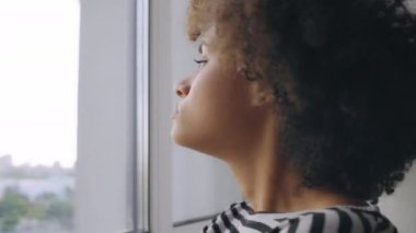 Uzaktan bakan düşünceli Afrikalı Amerikalı kadın kendini yalnız hissediyor.