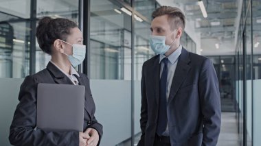 Tıp maskeli iki meslektaş ofiste projeyi tartışıyor, salgın güvenliği.