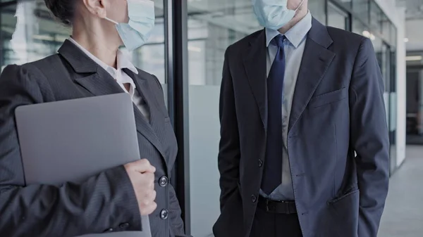 Business man and woman wearing medical masks in office, work during pandemic