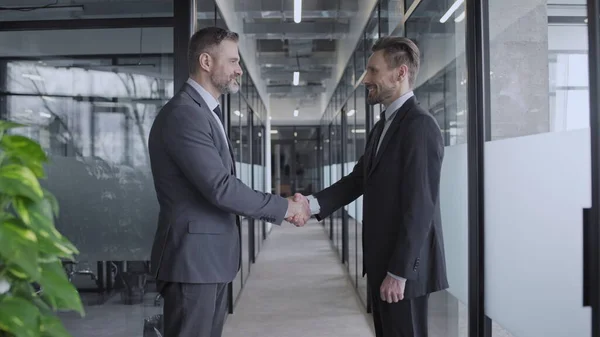Şirket ofisindeki başarılı erkek iş ortaklarının el sıkışması, işbirliği
