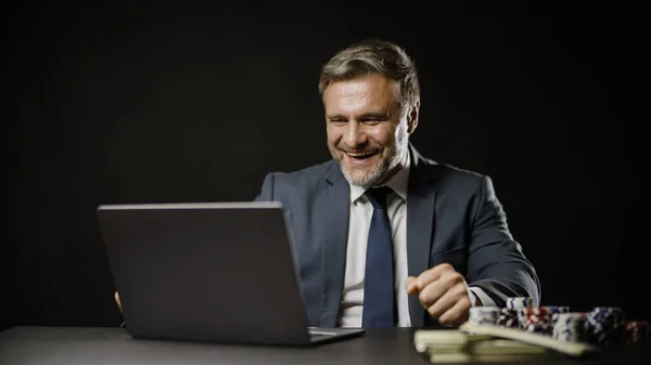 İnternette kumar oynayan heyecanlı iş adamı laptopu kullanıyor ve kazanıyor.