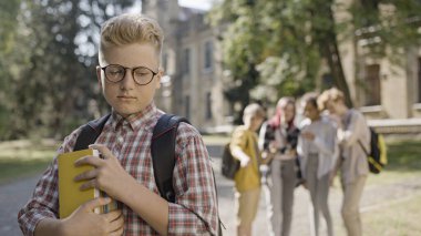 Popüler sınıf arkadaşlarıyla dalga geçen kendine güveni olmayan akıllı okul çocuğu.