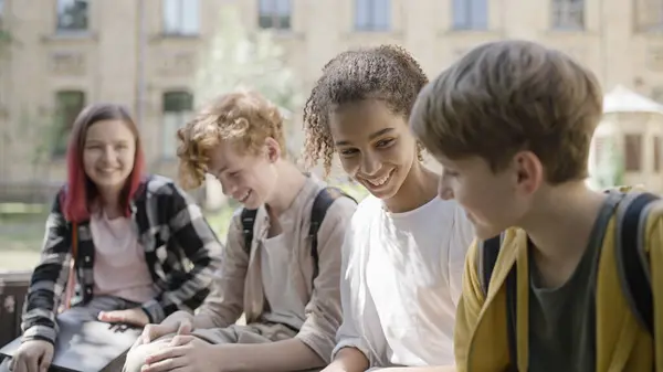 Mola sırasında konuşan ve gülen çok ırklı okul arkadaşları eğleniyor.