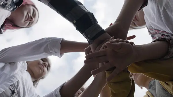 Mutlu çocuklar el ele tutuşuyor, birlikte hareket etmeye hazır, takım çalışması becerileri eğitiyor.