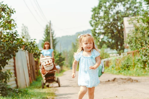 一个穿蓝色衣服的小女孩赤脚跑向妈妈在草地上 — 图库照片