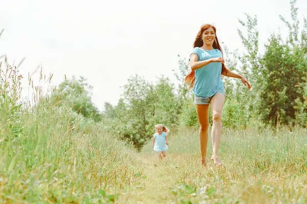 Filha corre para sua mãe na grama — Fotografia de Stock