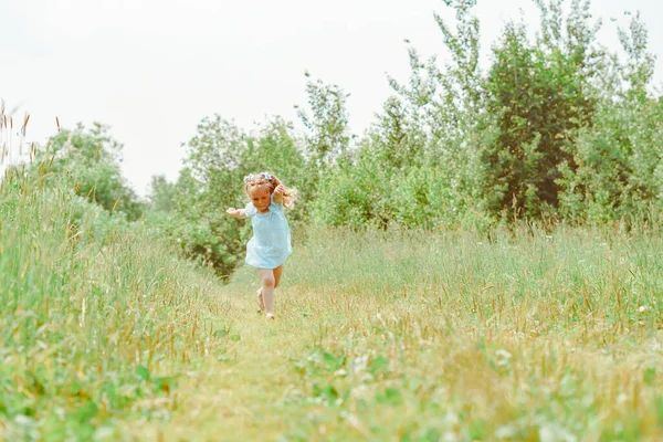 Bir çocuk çimenlerde koşar, küçük bir kız çayırda oynar. — Stok fotoğraf