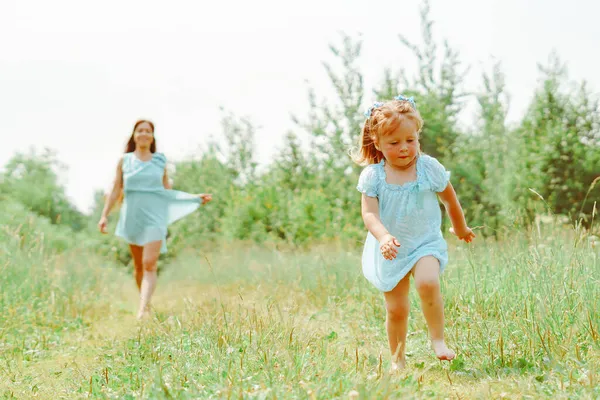娘は草の上で母親に向かって走る — ストック写真