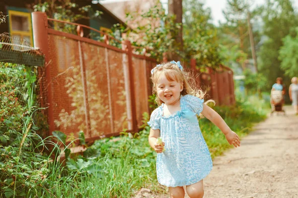 一个穿蓝色衣服的小女孩赤脚跑向妈妈在草地上 — 图库照片
