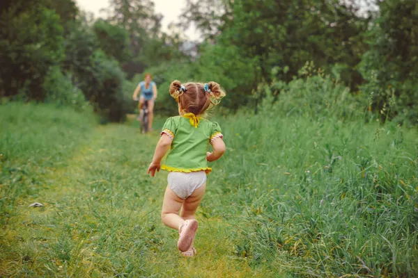 Uma criança corre na grama, uma menina brinca no prado — Fotografia de Stock