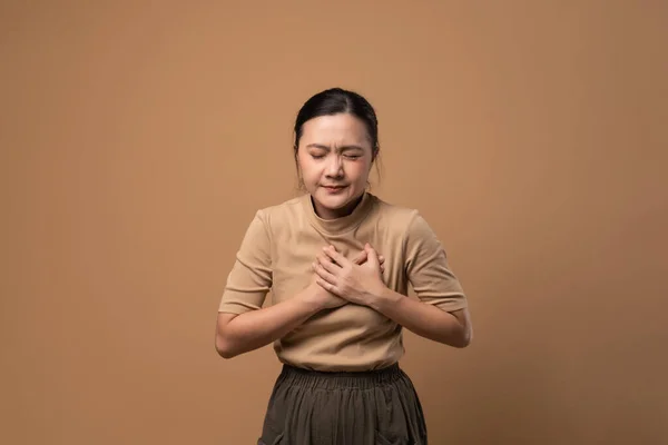 アジアの女性はベージュの背景に隔離された胸の痛みに苦しんでいた — ストック写真