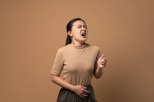 アジアの女性は喉が痛くて咳がしてくしゃみをしてベージュ色の背景に孤立して立っていた — ストック写真