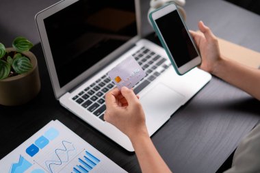 Kadın ellerinin kredi kartı ve akıllı telefonların merkez ofisteki ekran masaüstünü gösterirken yakın plan fotoğrafını çek..