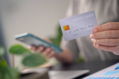 İnternetten alışveriş yapan kadınların ellerinde kredi kartı kartlarıyla akıllı telefondan mesaj yazarken yakın plan çekimleri..