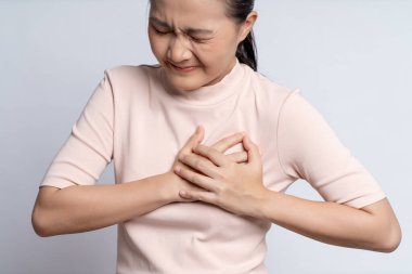 Asyalı kadın hastaydı. Göğüs ağrısı vardı. Beyaz arka planda tek başına duruyordu..