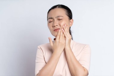 Asian woman was sick with toothache touching her cheek and standing isolated on white background.
