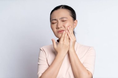 Asian woman was sick with toothache touching her cheek and standing isolated on white background.