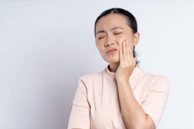 Asian woman was sick with toothache touching her cheek and standing isolated on white background.