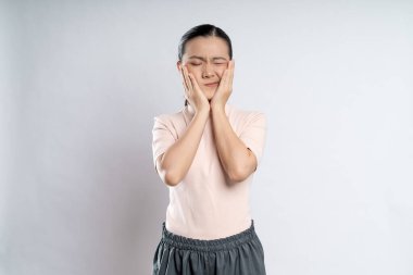 Asian woman was sick with toothache touching her cheek and standing isolated on white background.