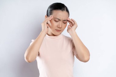 Asian woman was sick with headache touching her head and standing isolated on white background.