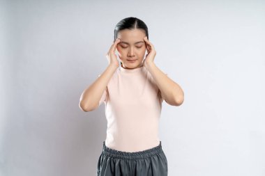 Asian woman was sick with headache touching her head and standing isolated on white background.