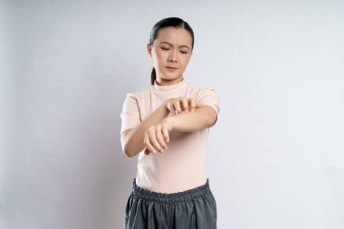 Asian woman was sick with irritate itching her skin, scratching her skin, standing isolated on white background.