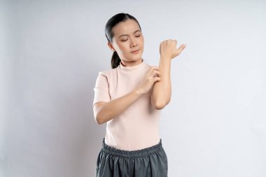 Asian woman was sick with irritate itching her skin, scratching her skin, standing isolated on white background.