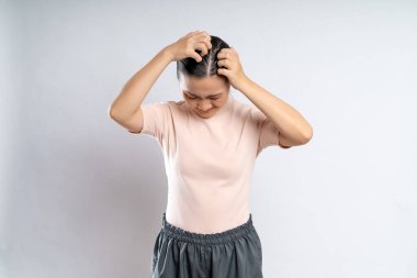 Asian woman was sick with irritate scratching her head, standing isolated on white background.