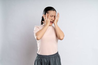 Asian woman scared and covering face by her hands standing isolated on white background.