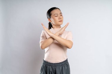 Asian woman showing arms crossed making stop sign standing isolated on white background.