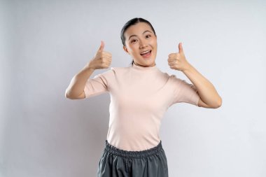 Asian woman happy showing thumb up, looking at camera, standing isolated on white background.