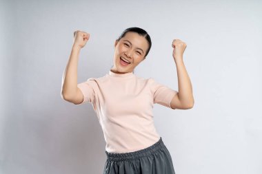 Asian woman happy confident showing her fist make a winning gesture standing isolated on white background.